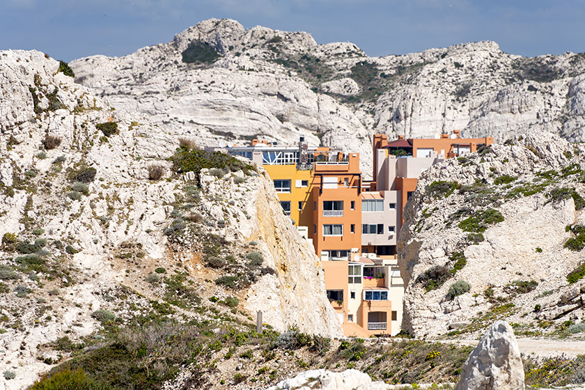 The colorful buildings emerge between the rocks